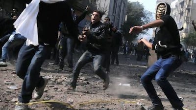 Protesters throw stones during clashes with riot police near Tahrir Square in Cairo last month. Mohmmed Hossam / AFP