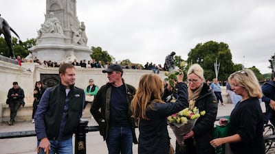 Well-wishers prepare a bouquet of flowers to leave at Buckingham Palace, on the first day of public mourning after the death of Queen Elizabeth II. Bloomberg