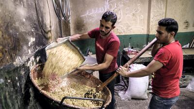 Egyptian confectioners add peanuts to melted sugar as they make sweets at a candy factory in the capital Cairo on November 2, 2019, ahead of celebrations of the Prophet Mohammed's birthday. AFP