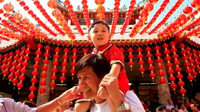 A man carries his child under traditional Chinese lanterns at a temple in Kuala Lumpur, Malaysia. Sadiq Asyraf / AP Photo