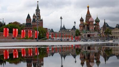 The Kremlin Wall with Spasskaya Tower, left, and St. Basil's Cathedral are reflected in a rainwater on the almost empty Bolshoy Moskvoretsky bridge decorated with red flags prior to celebrating Victory Day in Moscow AP