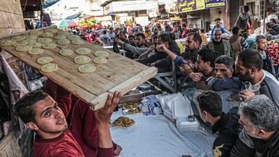 A Palestinian man carries a tray of qatayef, traditional Arabic dumplings, in Rafah, southern Gaza. AFP
