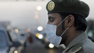 A Saudi police officer wears a surgical mask as he checks passengers and vehicles at Al-Shimaisi passport checkpoint, between Jeddah and Mecca,. AP Photo / Amr Nabil