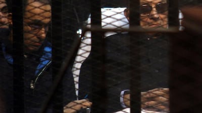 Egypt's former president Hosni Mubarak and his son Gamal sit behind bars during a court hearing (AFP PHOTO / STR)