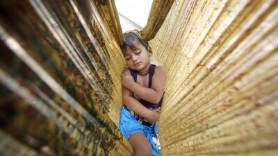 A child sleeps in a hammock made of cloth on a roadside in New Delhi. Rajat Gupta / EPA