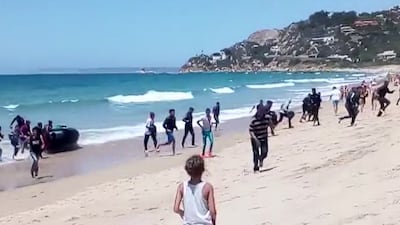 Migrants scatter from a rubber dingy beached on the coast at Cadiz, southern Spain. Carlos Sanz via AP