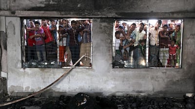 People watch the rescue operation after a devastating fire at the dyeing section of two-storey Aswad Composite Mills at Maona, Gazipur, Bangladesh. Abir Abdullah / EPA