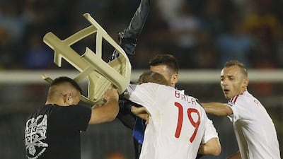 A Serbia fan, with a plastic stool, attacks Albania's Bekim Balaj as his teammates Ansi Agolli, right, and Nenad Tomovic, obscured, try to defend him. Marko Djurica / Reuters