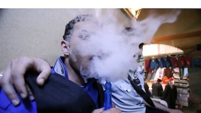 An emo smokes a shisha as its smoke obscures his identity in the city of Najaf.