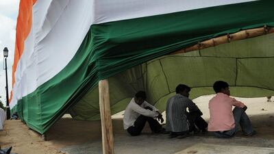 Indian men sit in the shade of a giant Indian flag banner at the Indian Gate monument during Independence Day celebrations in New Delhi on August 15, 2012. Roberto Schmidt / AFP Photo