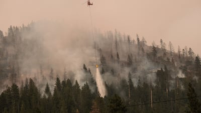 A helicopter drops water on a brush fire in California. Bloomberg