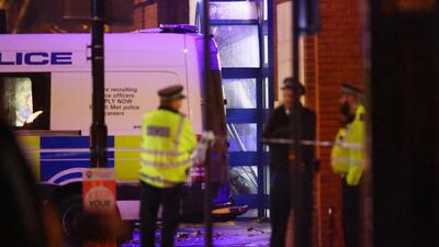 Police officers stand at the entrance, as debris is seen where the front of a car crashed into the Edmonton Police Station, in Enfield north London. Reuters