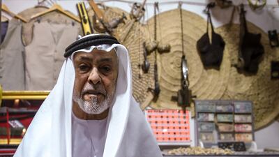 Bin Hathbour sets up his display of old model dhow boats, pearls, wooden clogs and other Emirati traditional items