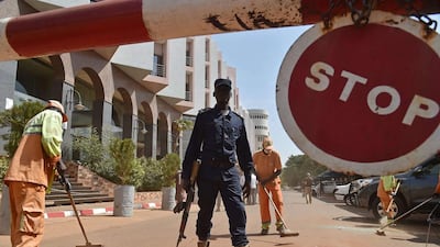 A Malian police officer stands guard as municipal workers clean outside the Radisson Blu hotel in Bamako on November 22, two days after a deadly attack. AFP Photo