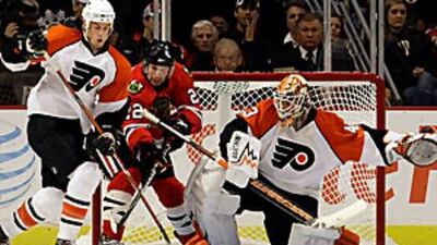 Chicago Blackhawks' Troy Brouwer, centre, battles for the puck with Philadelphia Flyers' Randy Jones, left, and the goalie Martin Biron during Chicago's 5-1 win