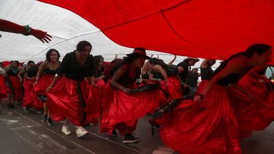 Women run under a giant Peruvian national flag during a march to mark International Women's Day, in Lima, Peru. AP