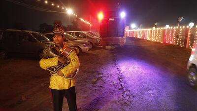 A member of Indian Brass band, specialized playing in weddings, waits to get back to their barrack after accompanying a wedding procession, in New Delhi.