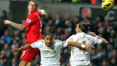 Liverpool`s Daniel Agger, left, leaps above Swansea City's Ashley Williams, centre, and Chico Flores, right. Geoff Caddick / EPA