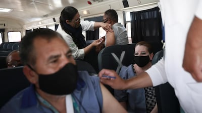 A health worker administers the Pfizer vaccine to maquiladora workers in a bus outside the Benito Juarez Olympic Stadium in Ciudad Juarez, Mexico. AP Photo