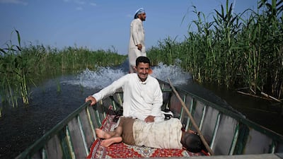 A boy rests as fishermen sail their boat through the Hawizeh Marshes in Maysan province