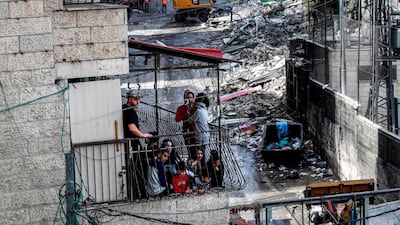 A Palestinian family watch from a balcony as Israeli bulldozers demolish shops in the Arab-inhabited Shuafat refugee camp in occupied East Jerusalem. AFP