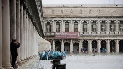 People stand beside a flooded St. Mark's Square in Venice, Italy. AP Photo