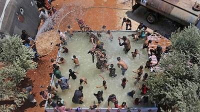 Syrian children play in a portable swimming pool set up by volunteers, at a camp for the displaced in the rebel-held town of Kafr Yahmul in Idlib.