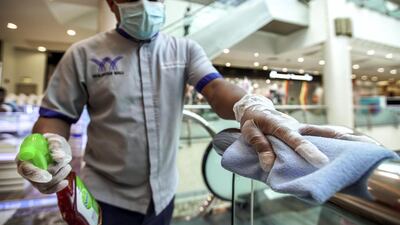A cleaner wipes down escalator hand rails at the Khalidiyah Mall in Abu Dhabi. Victor Besa / The National