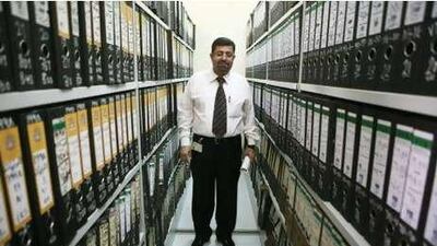 Dr Adnan Abbas stands among an archive of death certificates. Below, a body handler puts a blood sample requested by the police in a bag at the morgue at Khalifa Medical City.