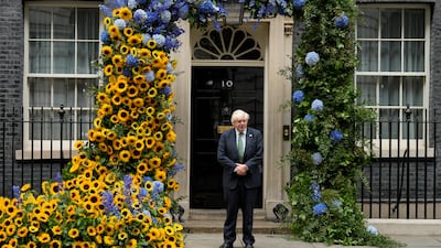 Britain's Prime Minister Boris Johnson outside No 10 Downing Street, central London, under a floral display installed to mark Ukraine's Independence Day. AP