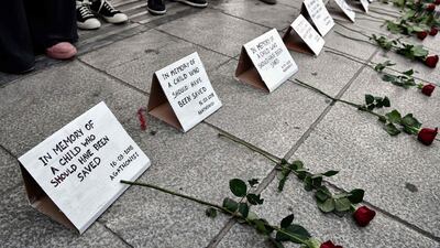 Migrants and solidarity groups stand behind roses lain on a pavement as they stage a protest in central Athens on April 4, 2018, against "Fortress Europe" and the EU-Turkey deal, which they allege delayed a rescue operation of a migrant boat by coast guards off Agathonissi island in March 2018. Louisa Gouliamaki / AFP