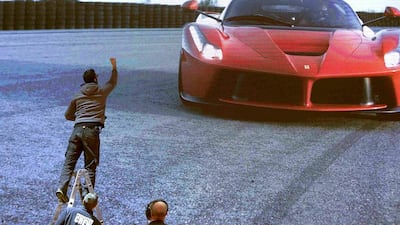 A worker stands on a ladder in front of a huge display at the exhibition stand of Ferrari ahead of International Motor Show in Geneva. Arnd Wiegmann / Reuters