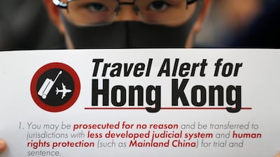 A protester holds up a banner warning of the dangers of traveling to Hong Kong at Hong Kong International Airport. AP Photo