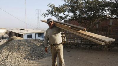 Franz Moreno poses for a photograph as he carries lumber to build a third storey on his mother’s house in Gosen City. Moreno works in construction and renovation. He lived for a while in Chile, but returned to Peru as the economy improved. Mariana Bazo / Reuters