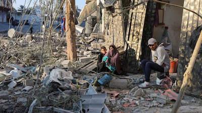 Palestinians sit among rubble at the site of an Israeli air strike on a house in Nuseirat, in the central Gaza Strip. Reuters