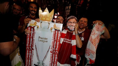 A Liverpool fan celebrates winning the Premier League with a cut out of manager Jurgen Klopp outside Anfield after Chelsea won their match against Manchester City. Reuters