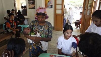 A Rohingya woman shows her baby to a nurse as another woman is examined by a doctor from the Ministry of Health at a hospital near the Dar Paing camp for internally displaced people in Sittwe, Rakhine state.