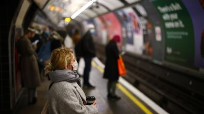 A woman wearing a face mask and holding a cup looks on at the Vauxhall tube station in London as passengers are told to stay home. Reuters.