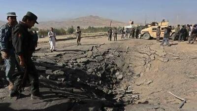 Afghan police near a crater at the scene of a suicide attack in Maidan Shar.