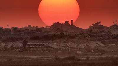 The sun sets behind destroyed buildings in Gaza. AFP