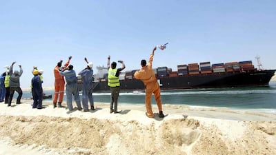 Egytpian workers wave towards a container ship sailing on the waterway of the new Suez Canal in Ismailia, Egypt. EPA