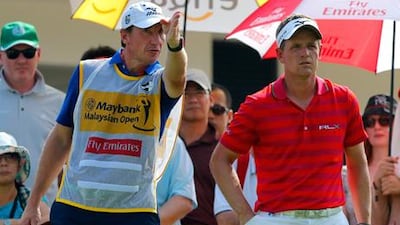 Luke Donald takes advice from his caddy at the first home of the Malaysian Open.