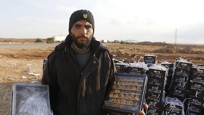 Bahaa Al Masri displays date-filled pastries and sesame biscuits he sells to Jordanians at the recently reopened Nassib border post in the Deraa province. AFP