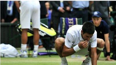 Novak Djokovic tastes the rye grass on Centre Court after his victory against Rafael Nadal on Sunday.