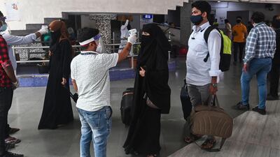 A health worker takes the body temperature of incoming passengers at a railway terminal. Restrictions were imposed in Mumbai by the state government because of a rising number of Covid-19 cases. AFP