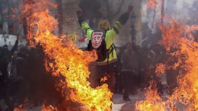 A yellow-vest protester wears a mask depicting French President Emmanuel Macron on which is written 'psycho'. AFP