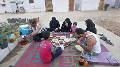 A family of Syrian refugees break their fasting outside their tent at a Syrian refugee camp in the Bekaa Valley, Lebanon. Bilal Hussein / AP