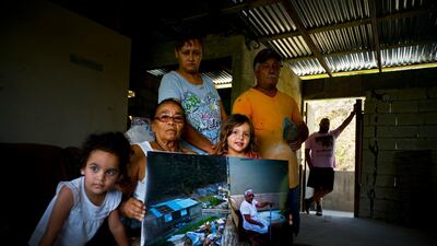 Juana Sostre Vazquez holds a printed photograph of her taken after Hurricane Maria destroyed her home. Last year's storm ripped Sostre's wooden home off its foundation in the central mountain highlands.