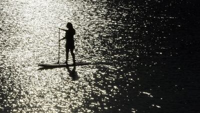 A woman stand-up paddle boarding on Lake Quannapowitt, Mass. Elise Amendola / AP Photo