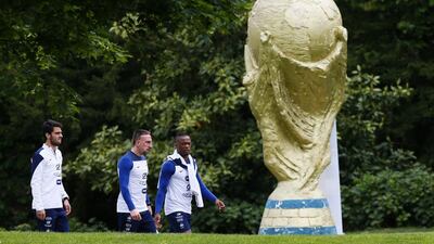 France players Clement Grenier (L), Franck Ribery (2nd L) and Patrice Evra walk beside a World Cup trophy sculpture before a training session in Clairefontaine-en-Yvelines, outside Paris, on May 23, 2014, as part of France's national football team's preparation for the upcoming 2014 World Cup in Brazil. Patrick Kovarik / AFP